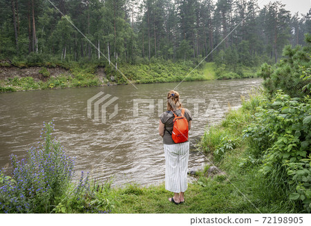 Woman admiring the flow of the river against the forest Woman admiring the flow of the river against the forest 72198905