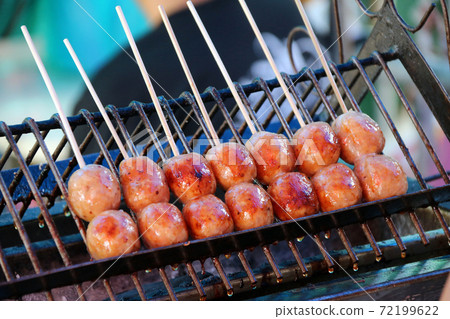 Thai sausage with wood stick grilling on the metal grill grate in the stove. Thai sausage with wood stick grilling on the metal grill grate in the stove. 72199622
