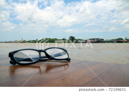 Beautiful view of Chaophraya River and foreground out focus, Glasses placed on the wooden table Beautiful view of Chaophraya River and foreground out focus, Glasses placed on the wooden table 72199631