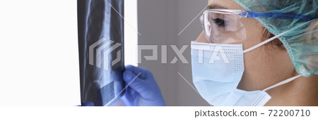 Doctor inprotective mask examines x-ray. Doctor inprotective mask examines x-ray. 72200710