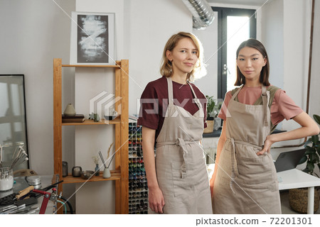 Two successful young intercultural craftswomen in aprons working in studio Two successful young intercultural craftswomen in aprons working in studio 72201301