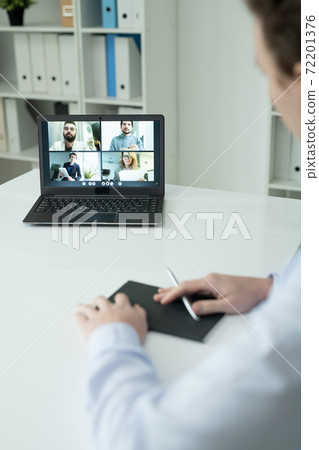 Several colleagues on laptop display looking at businessman sitting by desk 72201376