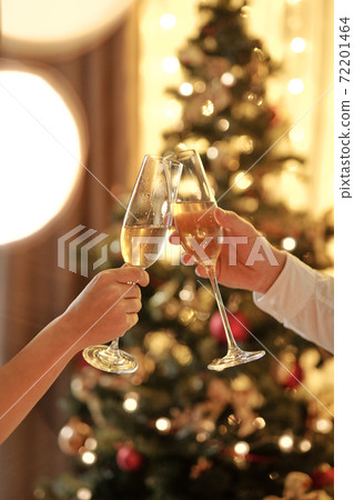 Hands of couple clinking with flutes of champagne while toasting for Christmas 72201464