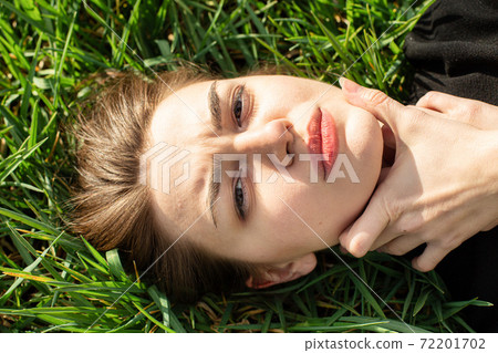 Girl with dark hair on grass Girl with dark hair on grass 72201702