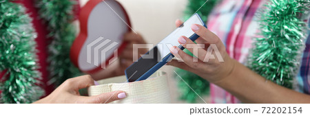 Female hands are holding and passing festive box with smartphone Female hands are holding and passing festive box with smartphone 72202154