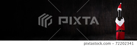 Wine bottle in Santa Claus Hat and Costume on wooden rustic background. Long banner 72202341