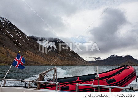 Icelandic flag and rubber boat sailing in a fjord, Iceland Icelandic flag and rubber boat sailing in a fjord, Iceland 72202529