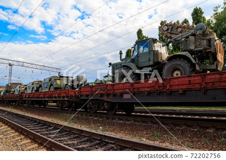 Cargo train carrying military vehicles on railway flat wagons Cargo train carrying military vehicles on railway flat wagons 72202756