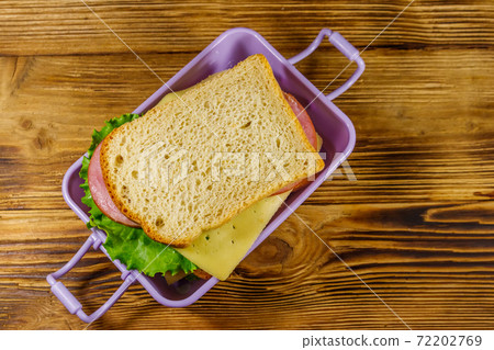 Lunch box with sandwiches on a wooden table. Top view 72202769