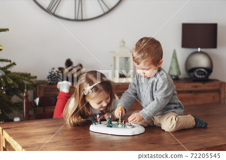 Sister and brother play with ceramic figurines for Christmas 72205545