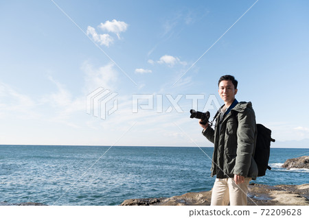 A man holding a camera toward the sea of Enoshima 72209628