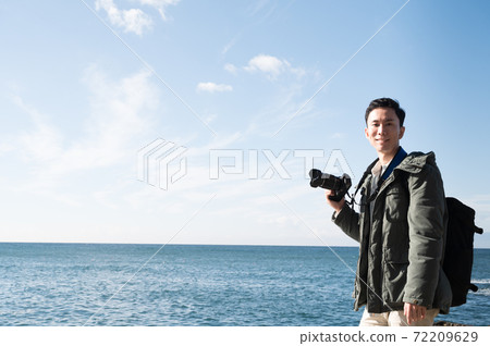 A man holding a camera toward the sea of Enoshima 72209629