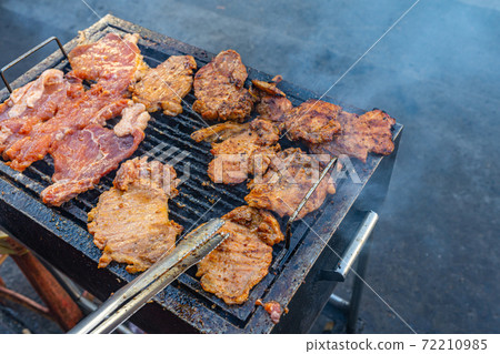 Grilling marinated pork chop on smoky charcoal pan Grilling marinated pork chop on smoky charcoal pan 72210985