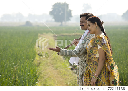 Happy Indian couple farmers examining crop in agricultural field Happy Indian couple farmers examining crop in agricultural field 72213188