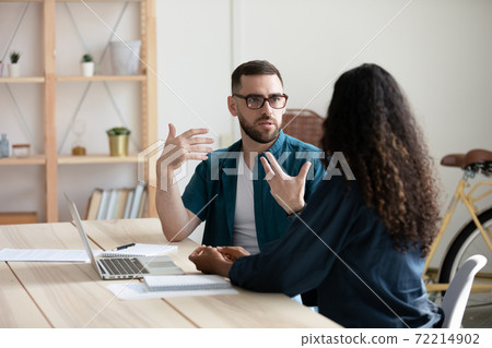 Focused diverse colleagues cooperate at team meeting in office 72214902