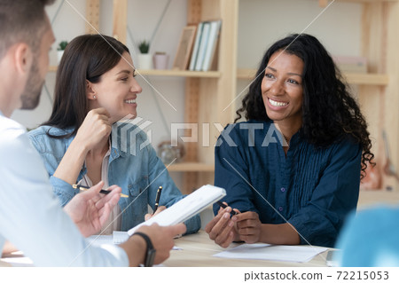 Smiling multiracial employees brainstorm at team office meeting Smiling multiracial employees brainstorm at team office meeting 72215053