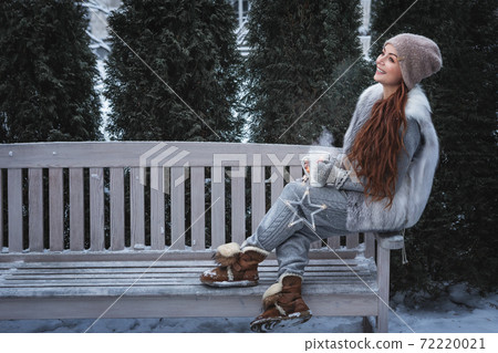 Woman with cup of tea in a park. Woman with cup of tea in a park. 72220021