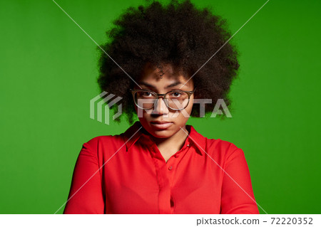 Discontent serious young African-American girl in glasses and red shirt Discontent serious young African-American girl in glasses and red shirt 72220352