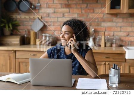 Distracted from computer work young biracial woman holding cellphone call. Distracted from computer work young biracial woman holding cellphone call. 72220735