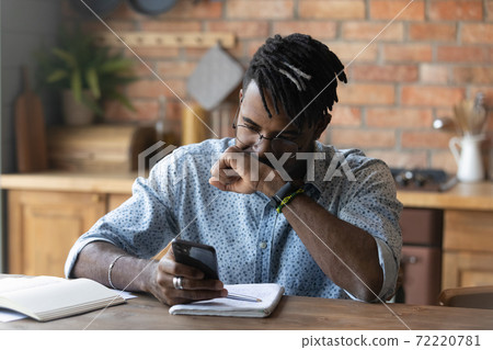 Stressed young biracial guy in glasses reading message with bad news. Stressed young biracial guy in glasses reading message with bad news. 72220781