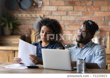 Focused young african american couple calculating monthly expenses. Focused young african american couple calculating monthly expenses. 72220925