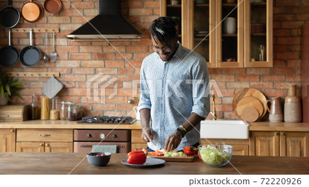 Happy young african american man enjoying cooking in kitchen. Happy young african american man enjoying cooking in kitchen. 72220926