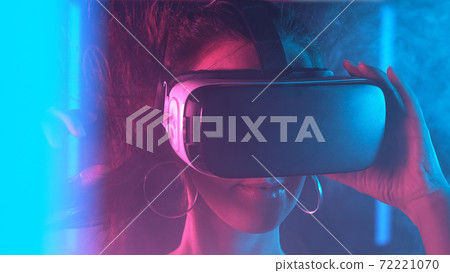Woman is using virtual reality headset. Neon light studio portrait. Woman is using virtual reality headset. Neon light studio portrait. 72221070