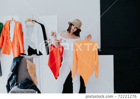 Portrait of happy young smiley brunette woman choosing outfit from wardrobe closet with stylish clothes Portrait of happy young smiley brunette woman choosing outfit from wardrobe closet with stylish clothes 72221276