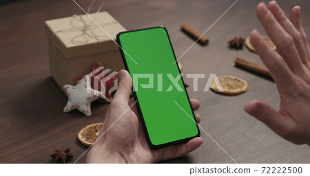 man hand chat with smartphone with green screen with christmas gifts and decorations on background man hand chat with smartphone with green screen with christmas gifts and decorations on background 72222500