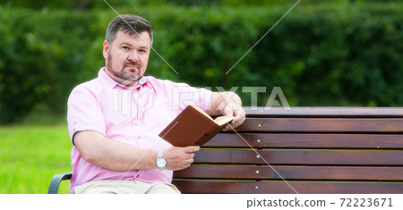Lonely man reading a book on the bench in his spare time Lonely man reading a book on the bench in his spare time 72223671