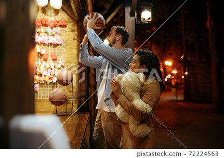 Couple play in shooting gallery, amusement park 72224563
