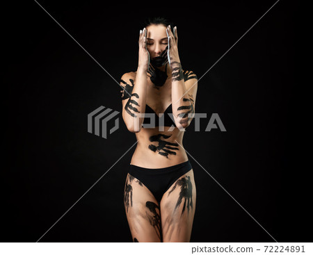a woman in underwear smeared with black paint on a black background a woman in underwear smeared with black paint on a black background 72224891