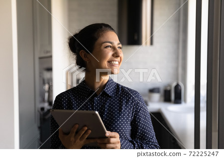 Happy excited mixed race woman dreaming distracted of tablet screen 72225247