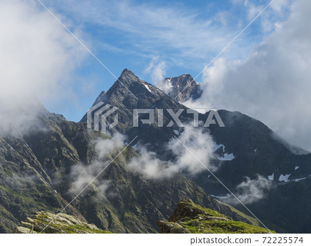 view on sharp snow-capped mountainpeaks at Stubai hiking trail, Stubai Hohenweg, Alpine landscape of Tyrol, Stubai Alps, Austria. Summer blue sky, white clouds. view on sharp snow-capped mountainpeaks at Stubai hiking trail, Stubai Hohenweg, Alpine landscape of Tyrol, Stubai Alps, Austria. Summer blue sky, white clouds. 72225574