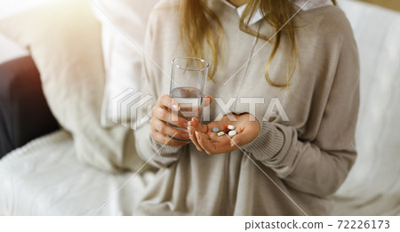 Close-up woman holding pills time to take medications, cure for headache. Medicine concept during self isolation and Coronavirus pandemic 72226173