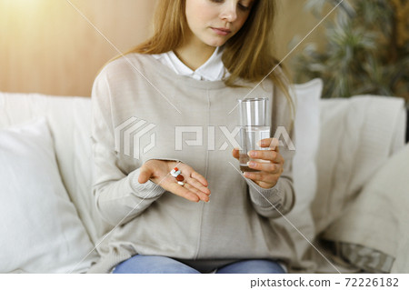 Close-up woman holding pills time to take medications, cure for headache. Medicine concept during self isolation and Coronavirus pandemic Close-up woman holding pills time to take medications, cure for headache. Medicine concept during self isolation and Coronavirus pandemic 72226182