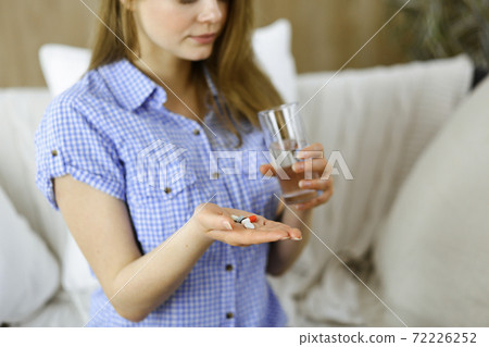 Close-up woman holding pills time to take medications, cure for headache, high blood pressure or cholesterol level remedy pain killer drugs. Medicine concept 72226252