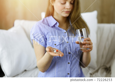 Close-up woman holding pills time to take medications, cure for headache. Medicine concept during self isolation and Coronavirus pandemic Close-up woman holding pills time to take medications, cure for headache. Medicine concept during self isolation and Coronavirus pandemic 72226253