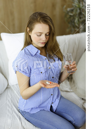 Close-up woman holding pills time to take medications, cure for headache, high blood pressure or cholesterol level remedy pain killer drugs. Medicine concept 72226258