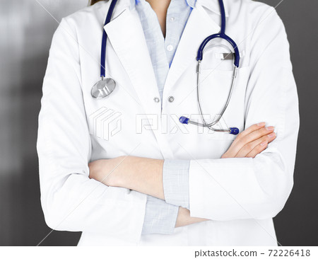 Unknown young woman doctor is standing with arms crossed in clinic. Medicine concept during Coronavirus pandemic 72226418