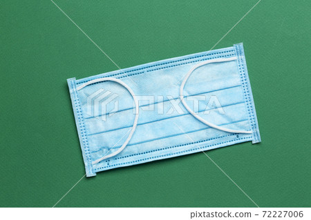 Surgical mask with rubber ear straps on a green background.  72227006