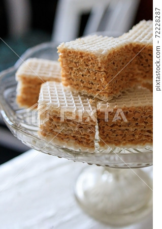 Waffle cake made of crispy waffle cakes with boiled condensed milk on a gray background. Quick sweet dessert. 72228287