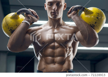 Fitness man pumping up muscles with kettlebell 72228913