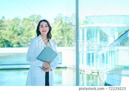 A female doctor with a smiling computer in a lab coat at the hospital A female doctor with a smiling computer in a lab coat at the hospital 72229223