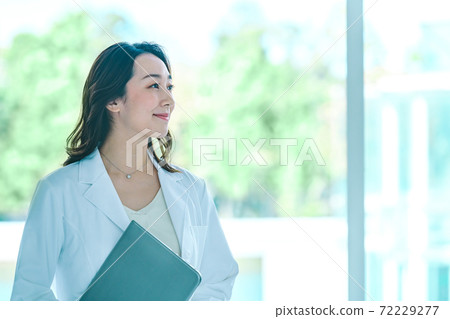 A female doctor with a smiling computer in a lab coat at the hospital A female doctor with a smiling computer in a lab coat at the hospital 72229277