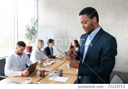 African Businessman Using Digital Tablet Browsing Internet Standing In Office 72229713
