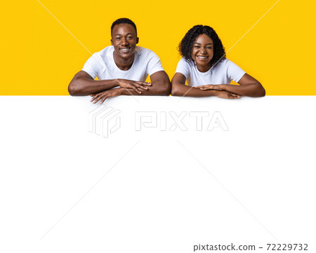 Happy african american couple leaning on advertisement board 72229732