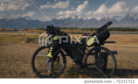 The mixed terrain cycle touring bike with bikepacking. The trip on multitrack bike, outdoor road in mountain snow capped. The mixed terrain cycle touring bike with bikepacking. The trip on multitrack bike, outdoor road in mountain snow capped. 72231722
