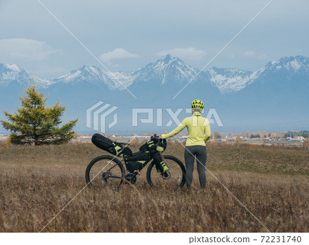 The woman travel on mixed terrain cycle touring with bikepacking. The traveler journey with bicycle bags. Sport tourism bikepacking. 72231740