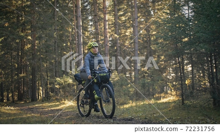 The woman travel on mixed terrain cycle touring with bike bikepacking. The traveler journey with bicycle bags. Magic forest park. The woman travel on mixed terrain cycle touring with bike bikepacking. The traveler journey with bicycle bags. Magic forest park. 72231756